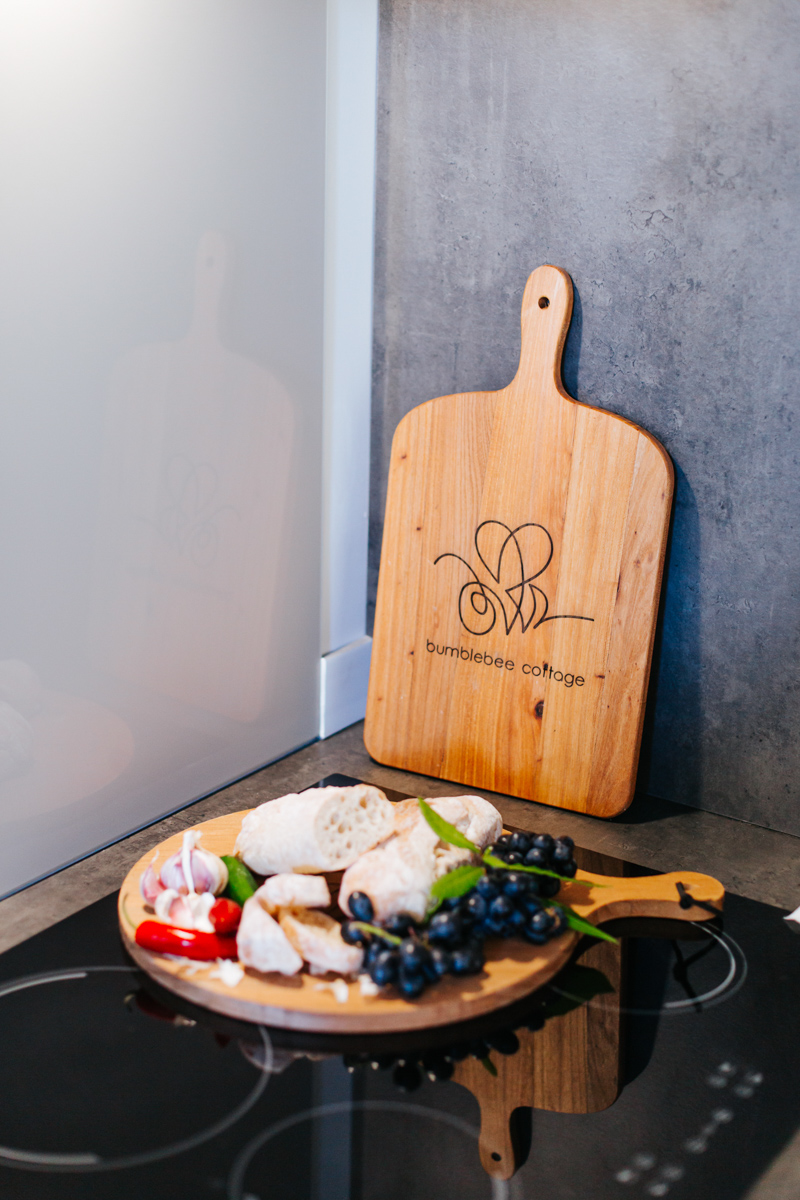 Engraved wooden paddle board with a food platter for a holiday let