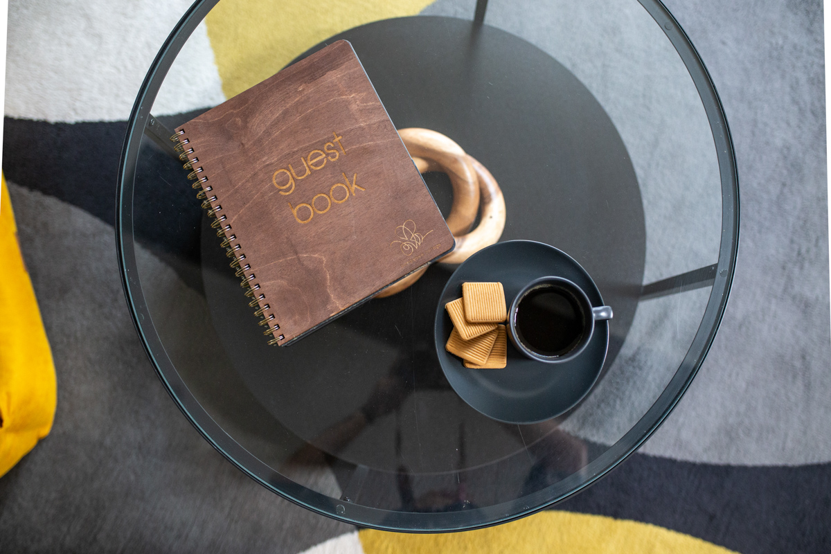 Engraved wooden guest book styled with coffee on a glass table